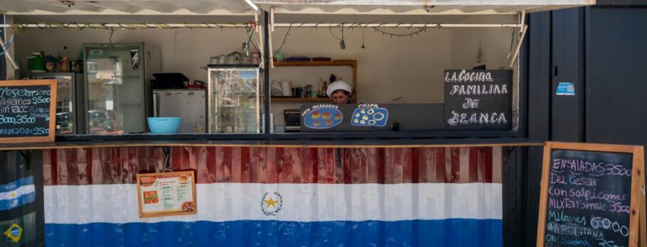 A imagem mostra Blanca Brizuela Duarte, que prepara e vende pratos típicos do Paraguai no “Pátio Gastronômico”, uma praça de alimentação ao ar livre construído na reserva ecológica próxima de Rodrigo Bueno.