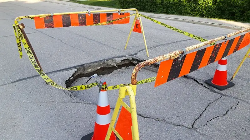 A foto mostra uma rua de asfalto rachada por conta do calor.