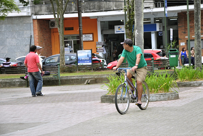 A foto mostra um homem andando de bicicleta em Joinville.