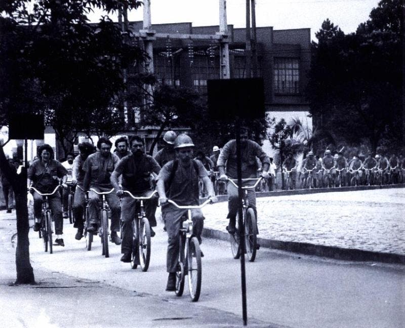 A foto mostra trabalhadores saindo da fábrica de bicicleta.