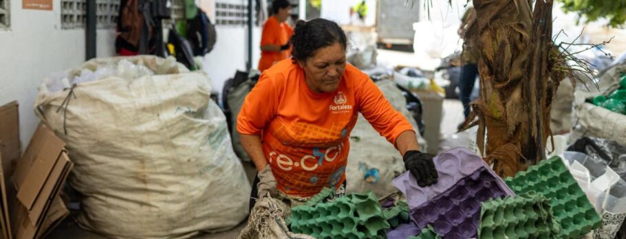 A foto mostra uma mulher organizando o lixo reciclável.